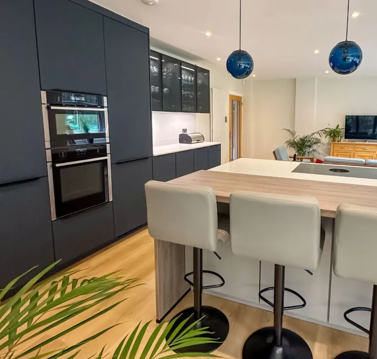Open-plan kitchen with grey cabinets, an island with bar seating, and blue pendant lights.