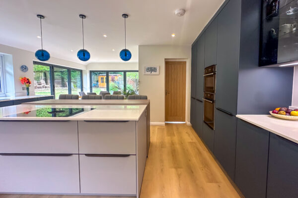 Spacious kitchen with light grey island, blue cabinets, and a view of the outdoor garden