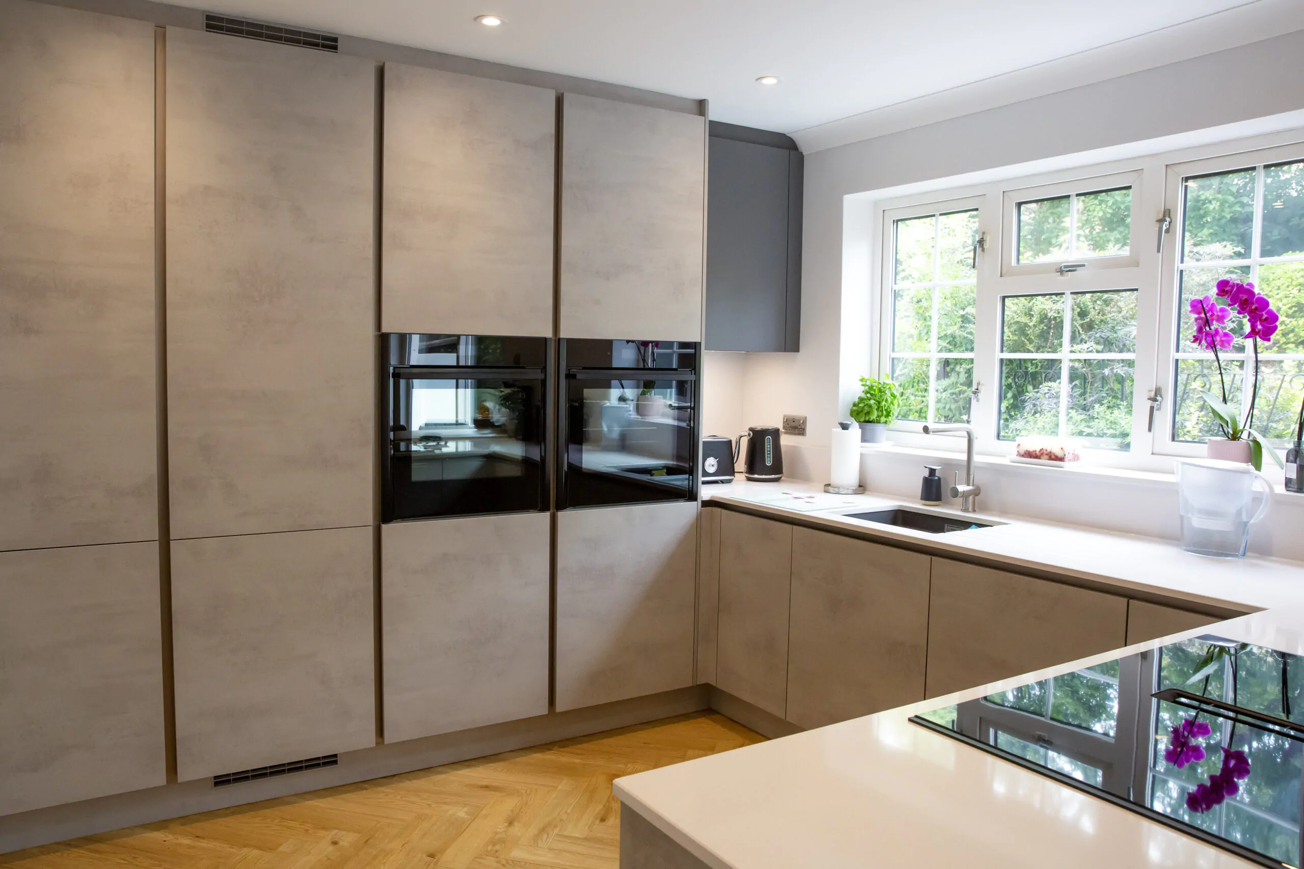 U-shaped kitchen with integrated appliances, white countertops, and a breakfast bar