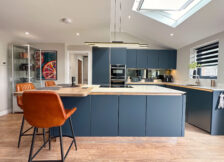 Modern kitchen showcasing a sleek design with dark cabinetry, white countertops, and oak breakfast bar.