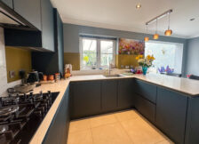 Spacious modern kitchen with integrated lighting, gold cabinets, and a 5-ring gas hob.