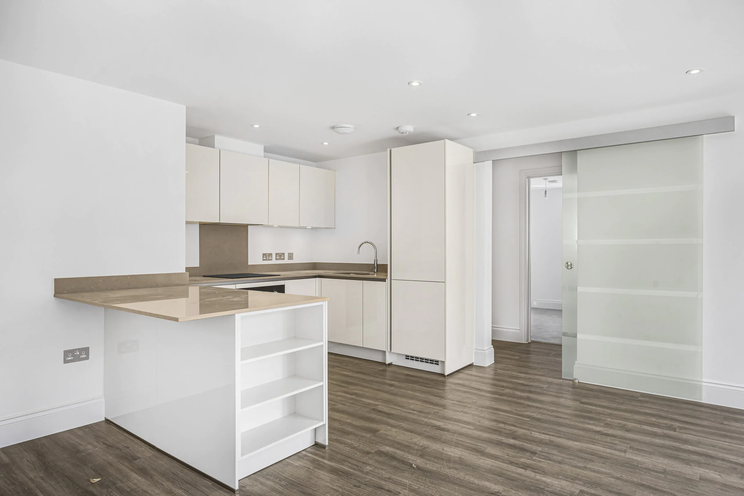 Modern white kitchen with integrated appliances, sleek worktops, and ample storage in Reading property development