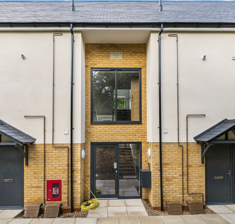 Close-up of a modern residential building with light brick facade and entry doors