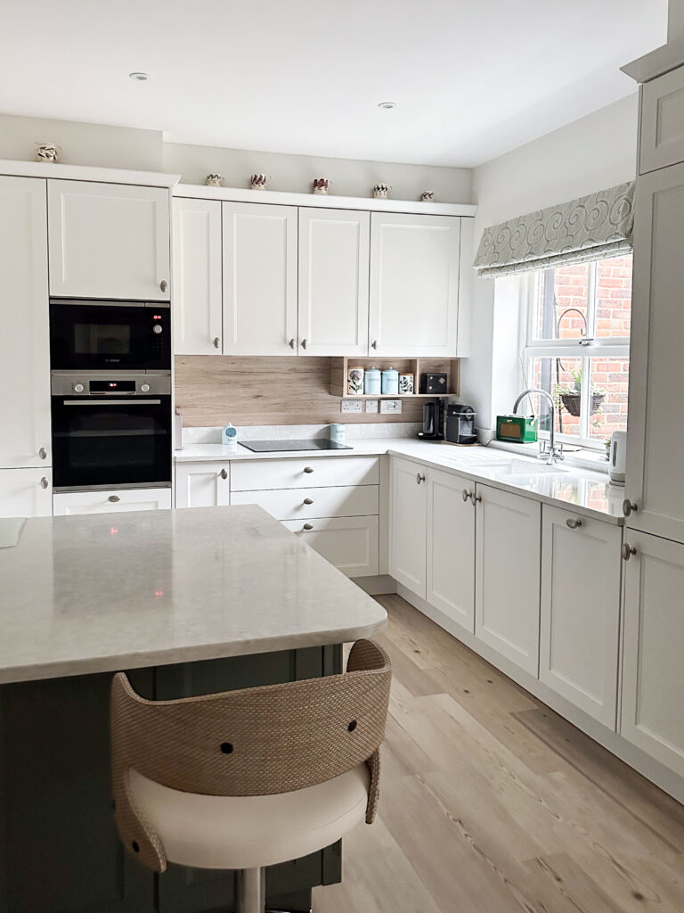 Elegant shaker cabinets in green and white with polished quartz worktop