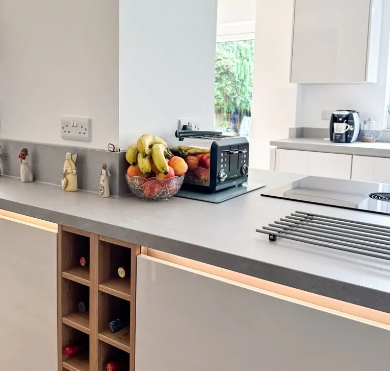 Wide view of modern kitchen with integrated appliances, breakfast bar, and pendant lights.