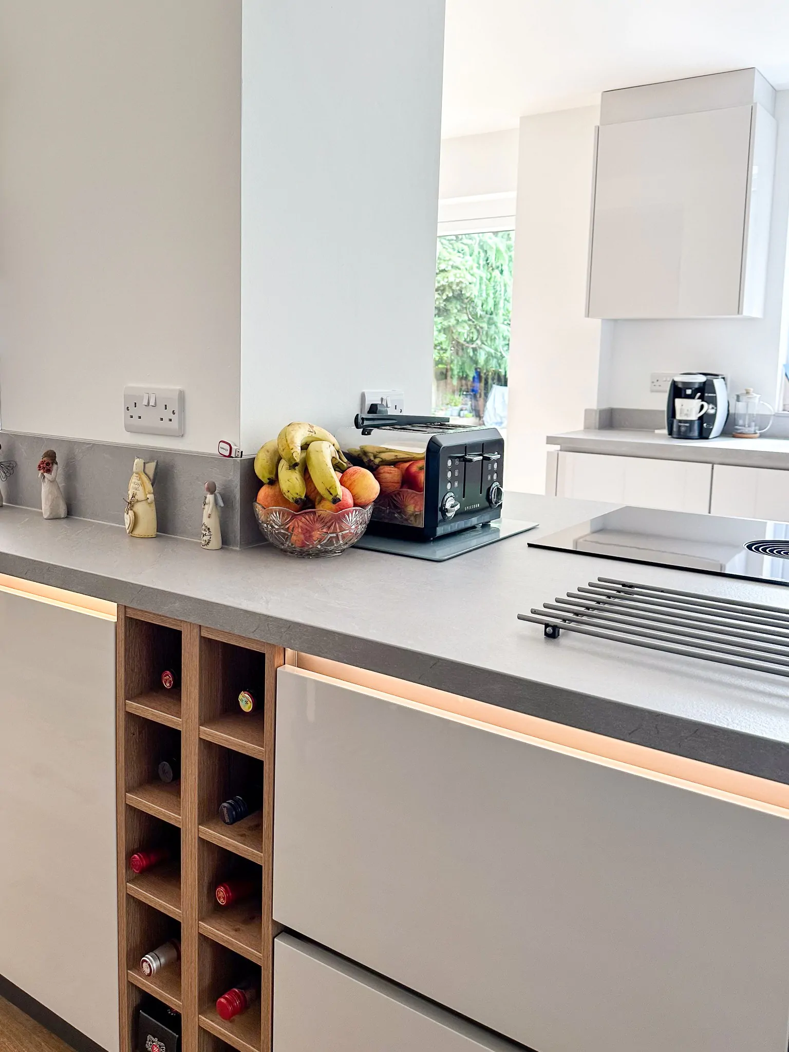 Wide view of modern kitchen with integrated appliances, breakfast bar, and pendant lights.