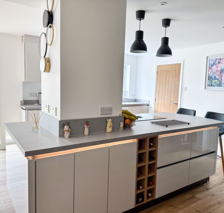 Modern kitchen with grey high-gloss cabinetry and a light breakfast bar with grey stools