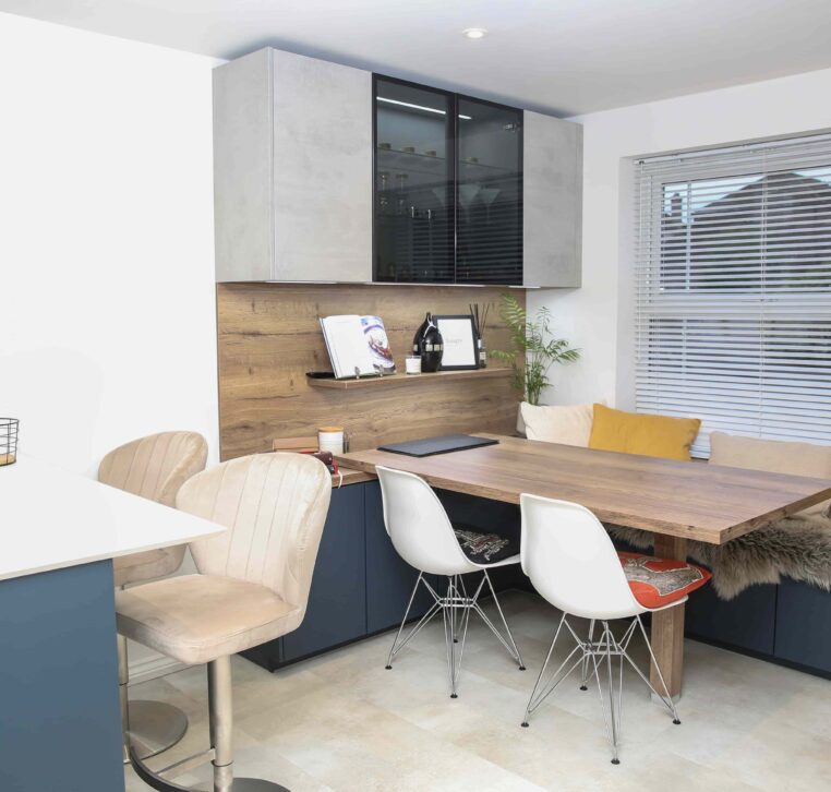 Cosy dining area with a wooden table, navy blue bench seating, mustard yellow cushions, and decorative shelving