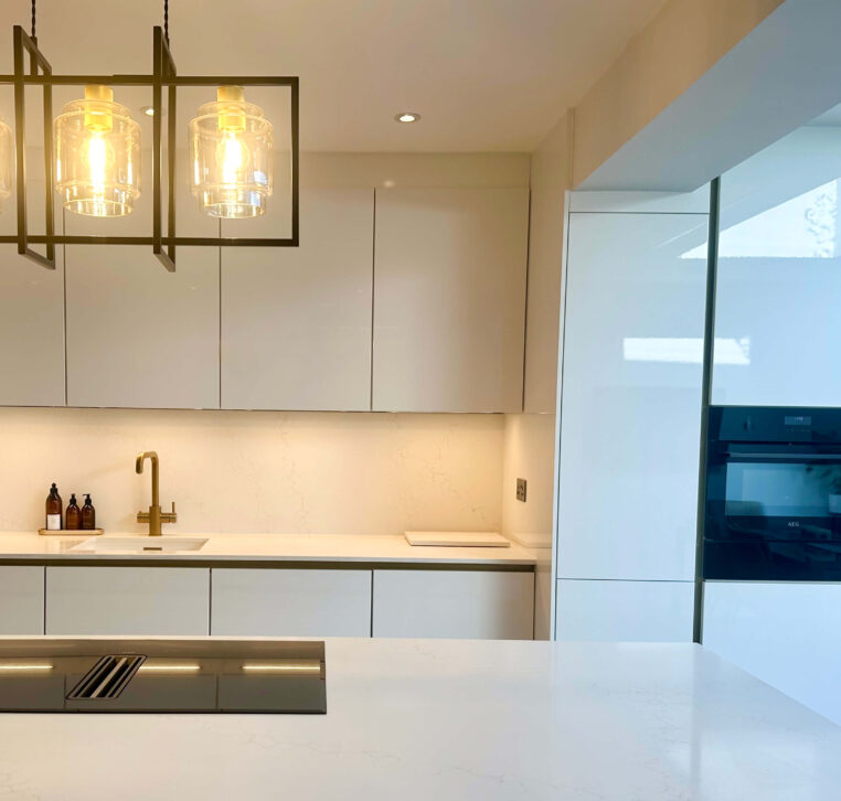 Stylish kitchen island with a black induction hob, gold pendant lights, and a modern sleek design.