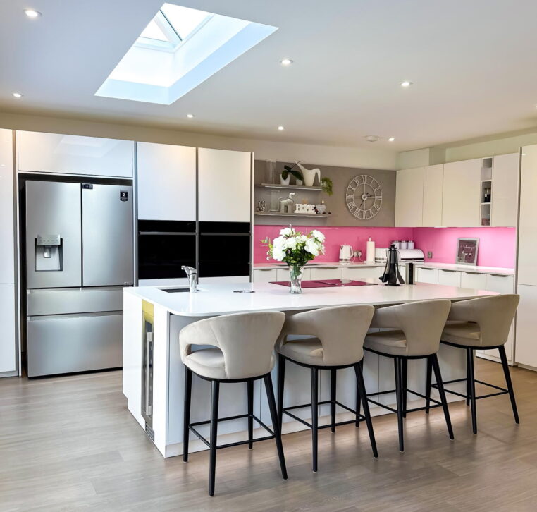 Spacious modern kitchen with large white island, skylight, bar stools, and built-in appliances.