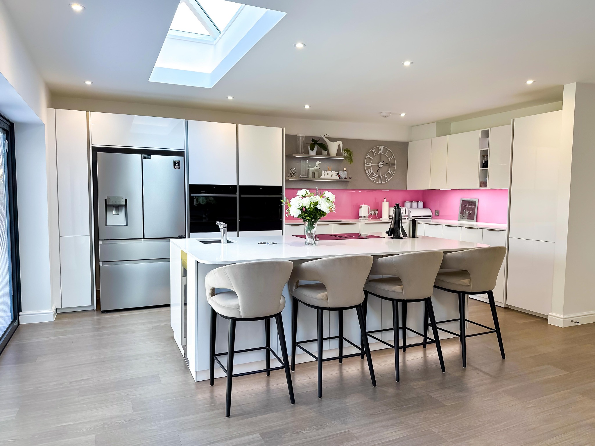 Close-up of a modern kitchen white island featuring a black sink and chrome faucet under recessed lighting.