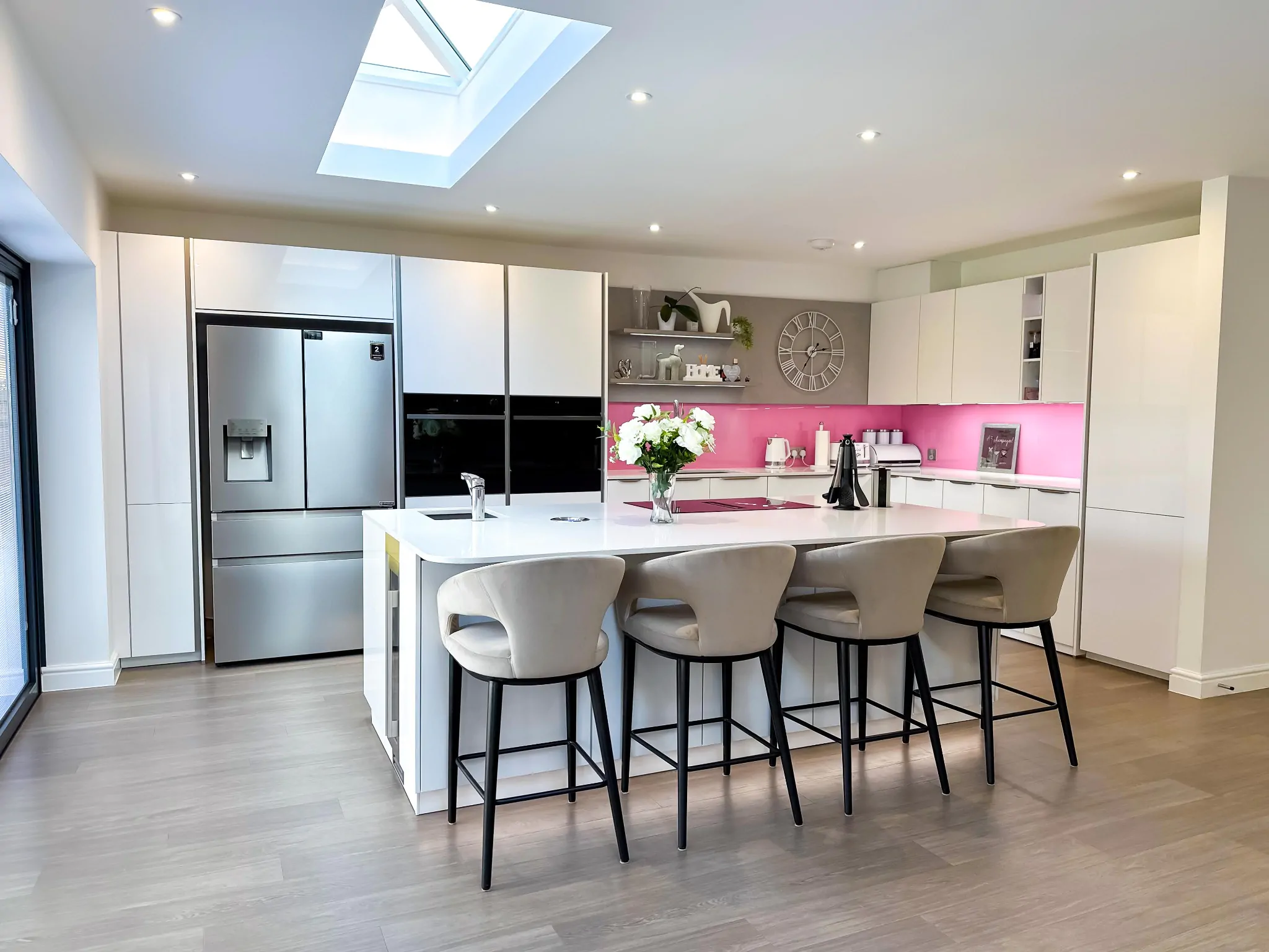 Close-up of a modern kitchen white island featuring a black sink and chrome faucet under recessed lighting.