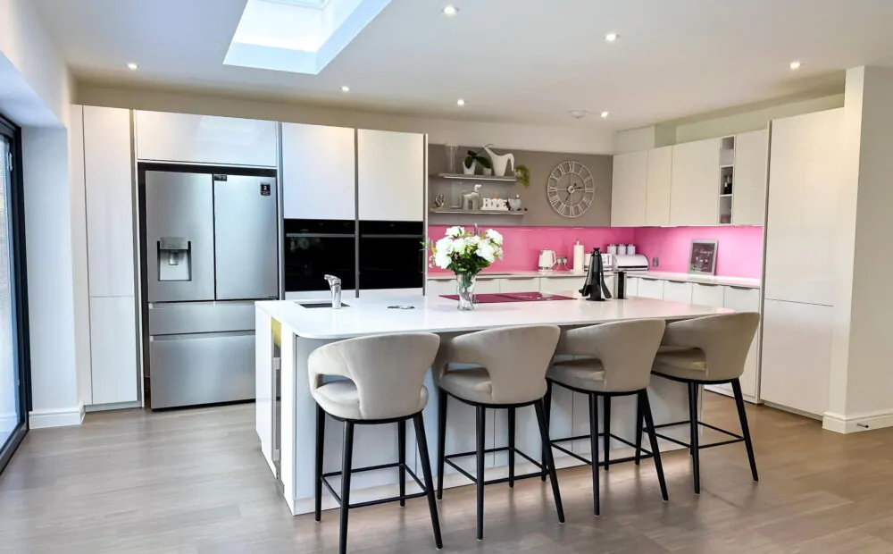 Close-up of a modern kitchen white island featuring a black sink and chrome faucet under recessed lighting.