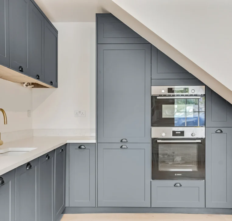 Corner kitchen layout with angled ceiling and shaker cabinetry