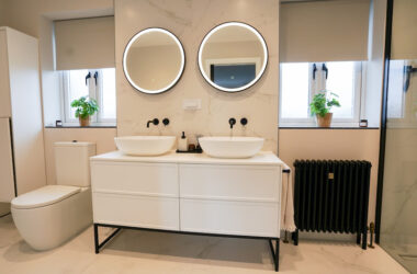 Double vanity unit with round LED backlit mirrors and wall-mounted taps.