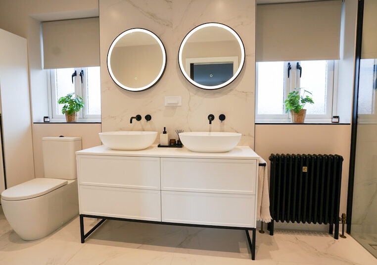 Double vanity unit with round LED backlit mirrors and wall-mounted taps.
