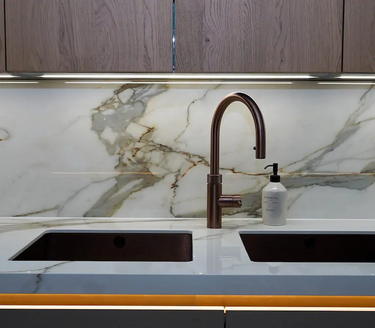 Double undermount sink set into marble worktop with LED lighting.
