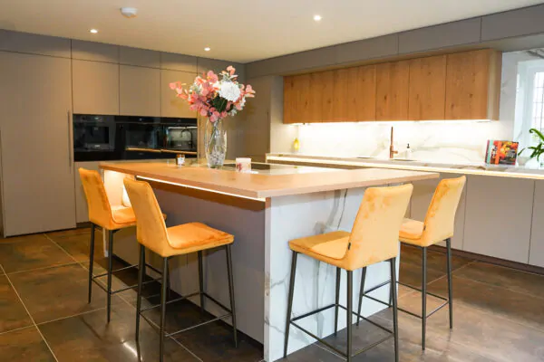 Modern handleless kitchen with marble waterfall island and grey cabinetry.