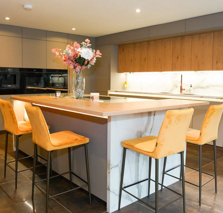 Modern handleless kitchen with marble waterfall island and grey cabinetry.