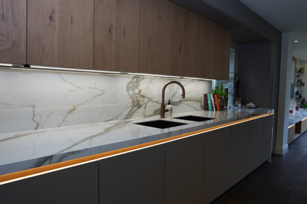 Marble splashback with integrated sink and bronze kitchen tap.