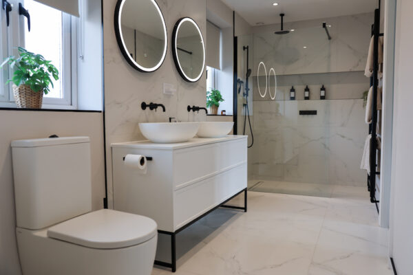 Modern bathroom with double vanity, wall-mounted taps, and walk-in shower.