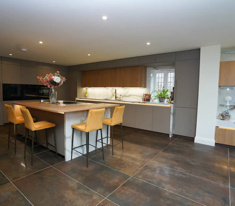 Modern grey handleless kitchen with marble splashback and island seating.