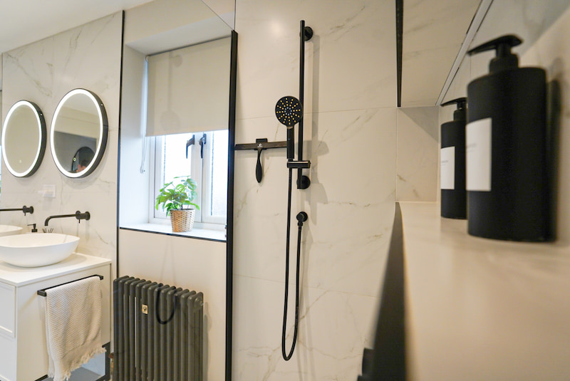 Walk-in shower featuring matte black fixtures and large-format wall tiles.