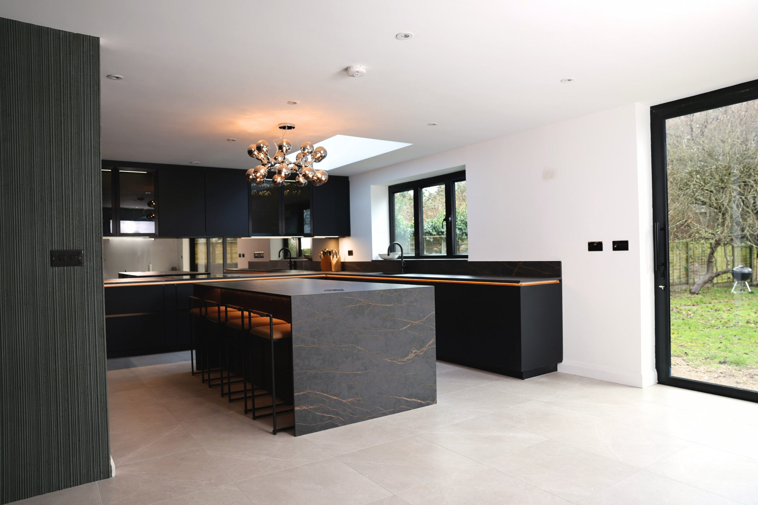 Bespoke dark kitchen with large statement island, pendant lighting and skylight
