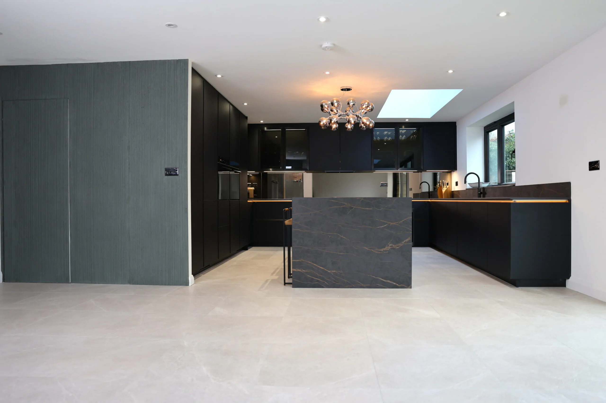 Bespoke open plan kitchen with dark units, central island and skylight