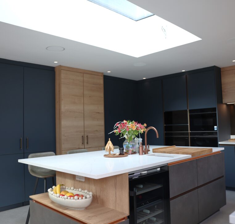 Handleless kitchen with dark blue cabinets, wood panelling and large central island