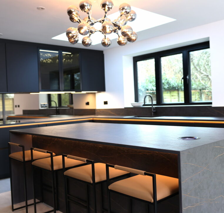 Kitchen island with bar seating, modern lighting and dark cabinetry detail