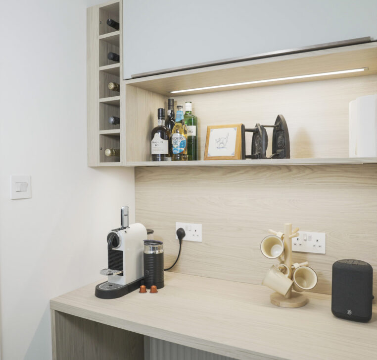 Modern kitchen coffee station with wood shelving, built-in wine rack and under-cabinet LED lighting