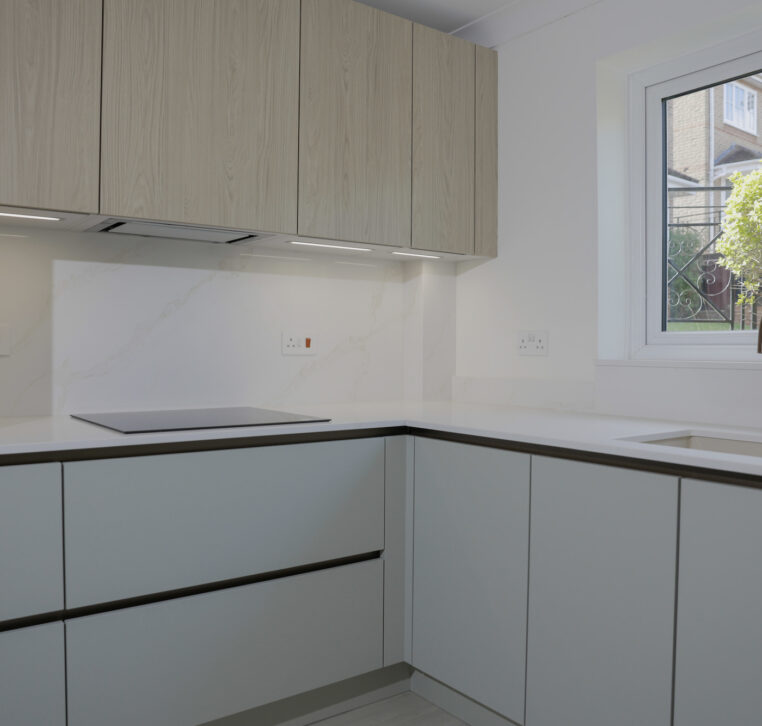 L-shaped modern kitchen with handleless cabinets, integrated hob and marble-effect splashback