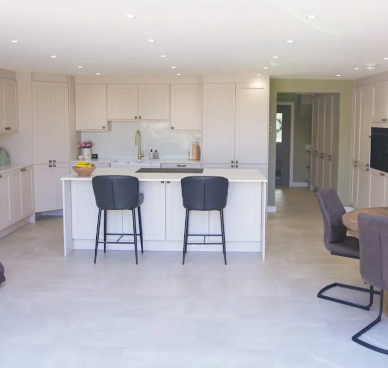 Open-plan shaker kitchen with central island seating and soft neutral cabinetry designed by MAS Kuchen.